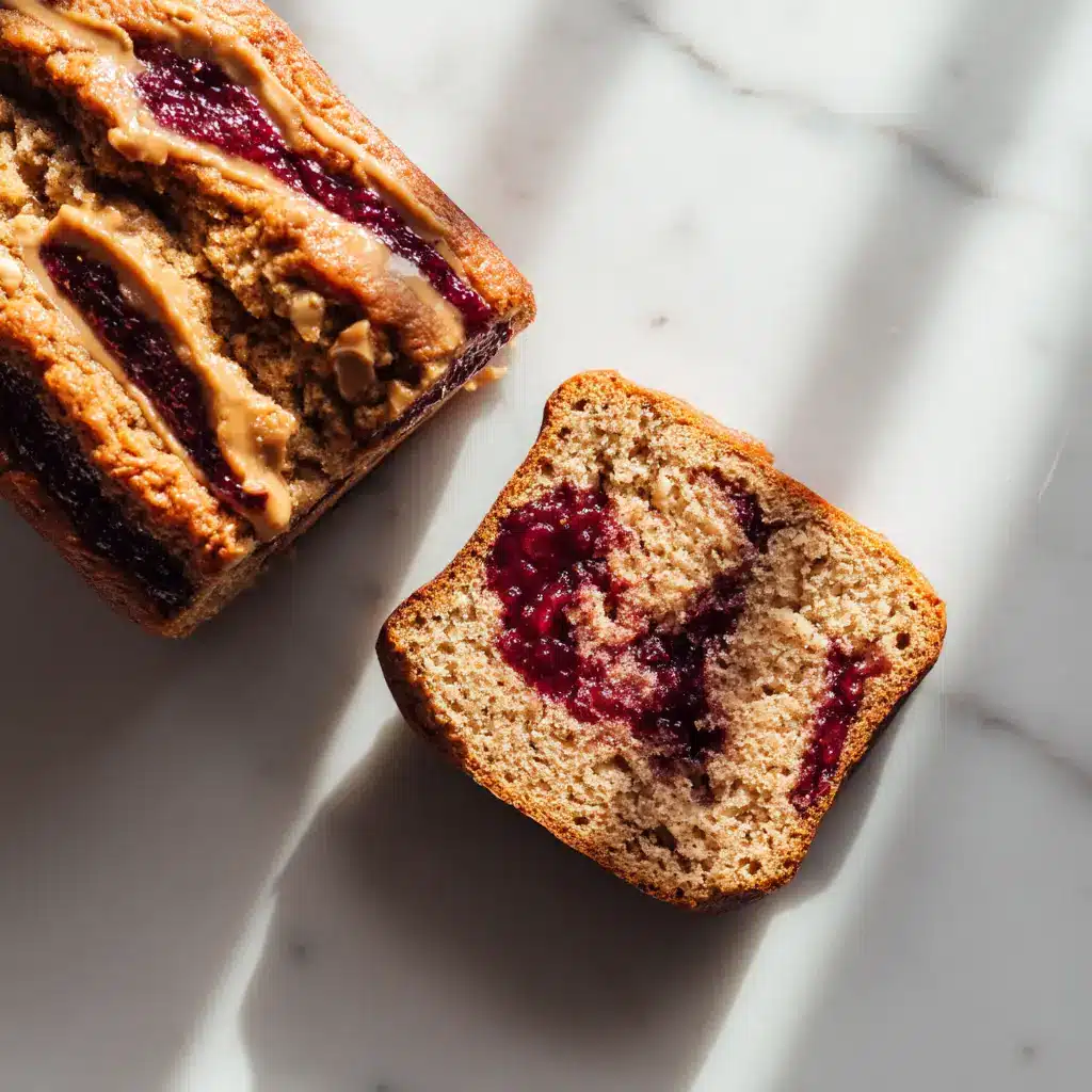 Golden-brown crust of a whole peanut butter and jelly banana bread loaf sitting in bright natural lighting.