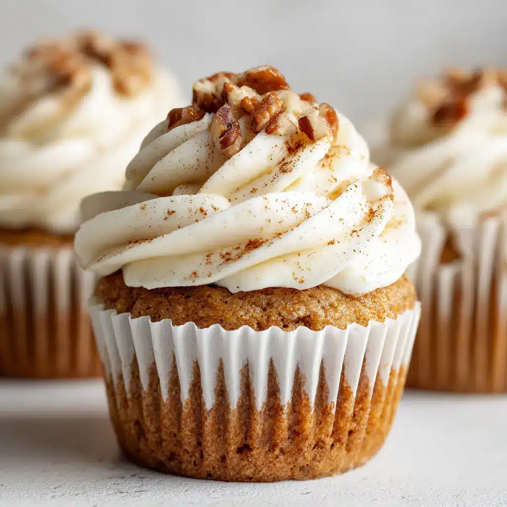 Close-up of freshly baked Banana Cinnamon Pecan Cupcakes in a white ridged paper liner with a moist, light brown crumb and thick cream cheese frosting.