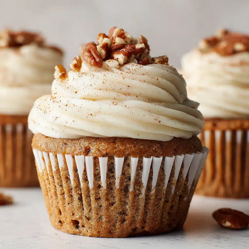 Macro view of the cream cheese frosting garnished with a dusting of cinnamon and chopped toasted pecans resting on the creamy peaks.