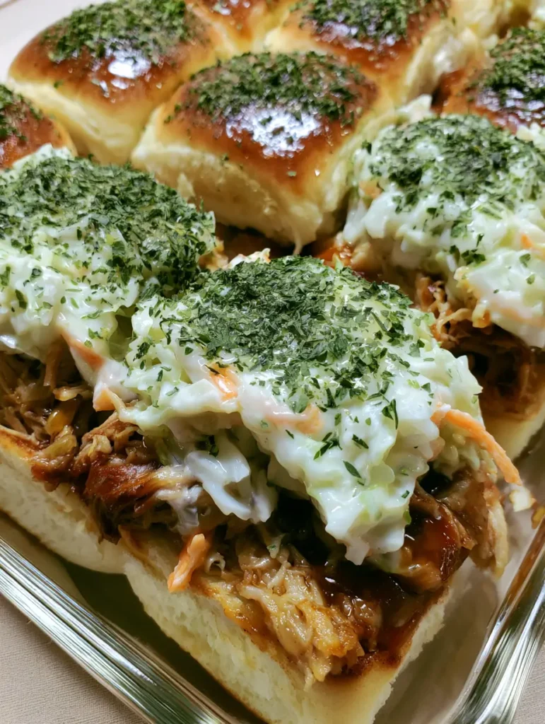 Pulled Pork Sliders with Creamy Slaw and Garlic Herb Butter 1 Close-up of shredded pork with dark amber glaze and creamy white coleslaw inside toasted sliders.